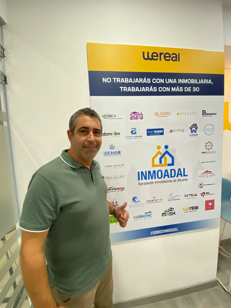 Andrés Broullón junto al cartel de INMOADAL, la Agrupación Inmobiliarias de Alicante, de la que forma parte Wereal